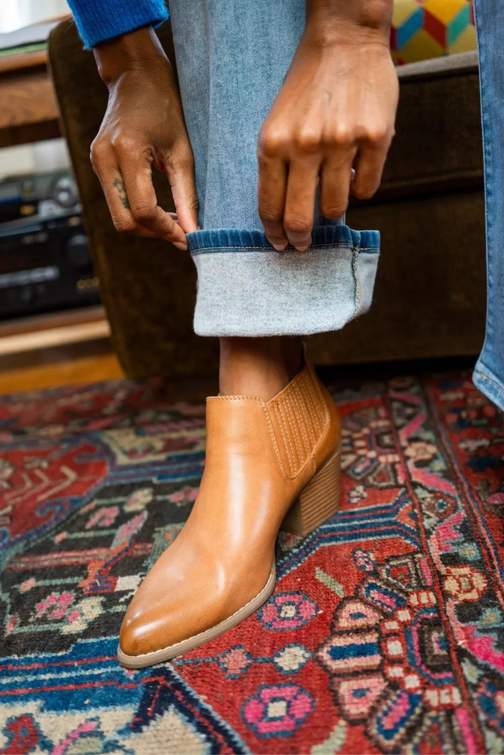 Close-up of light wash bootcut jeans cuffs and tan ankle boots