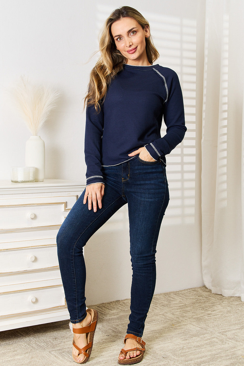 Dark blue long raglan sleeve round-neck top with white trim at collar, cuffs, and hem