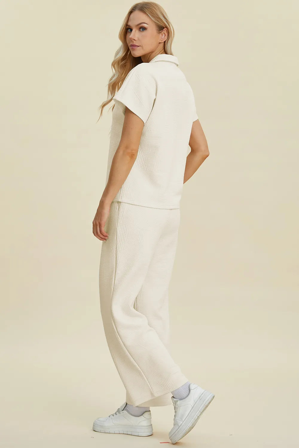 Cremefarbenes Set aus Polohemd und Hose, seitliche Ansicht von hinten mit weitem Bein