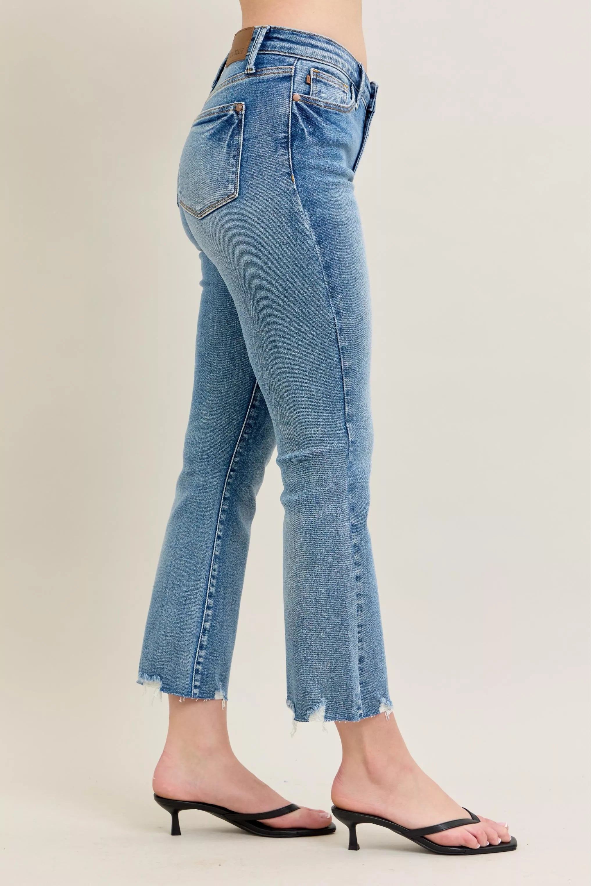 Medium-wash kick flare jeans, side/back angle with frayed destroy hem