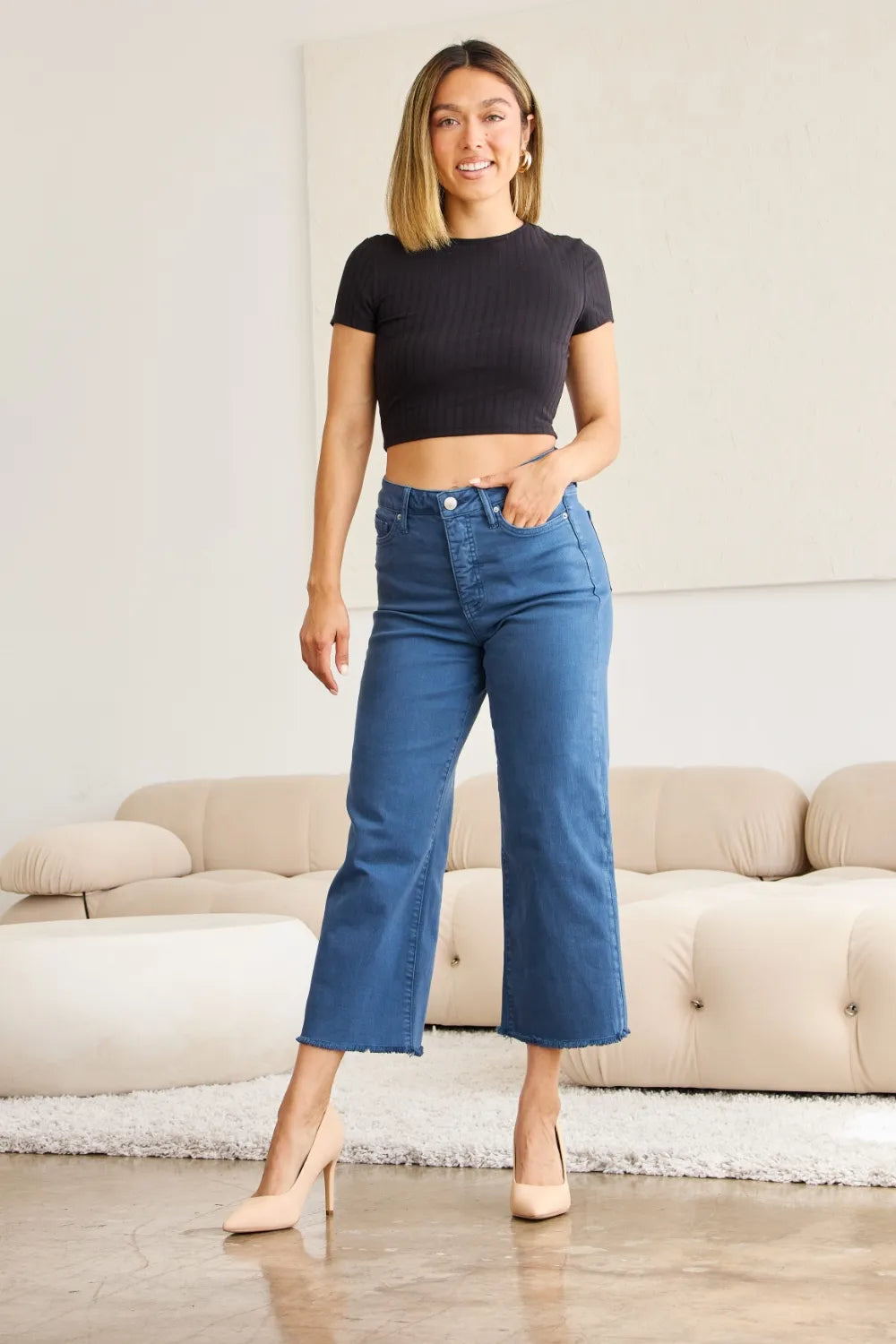 High-waist dark denim jeans with button fly and raw frayed ankle hem