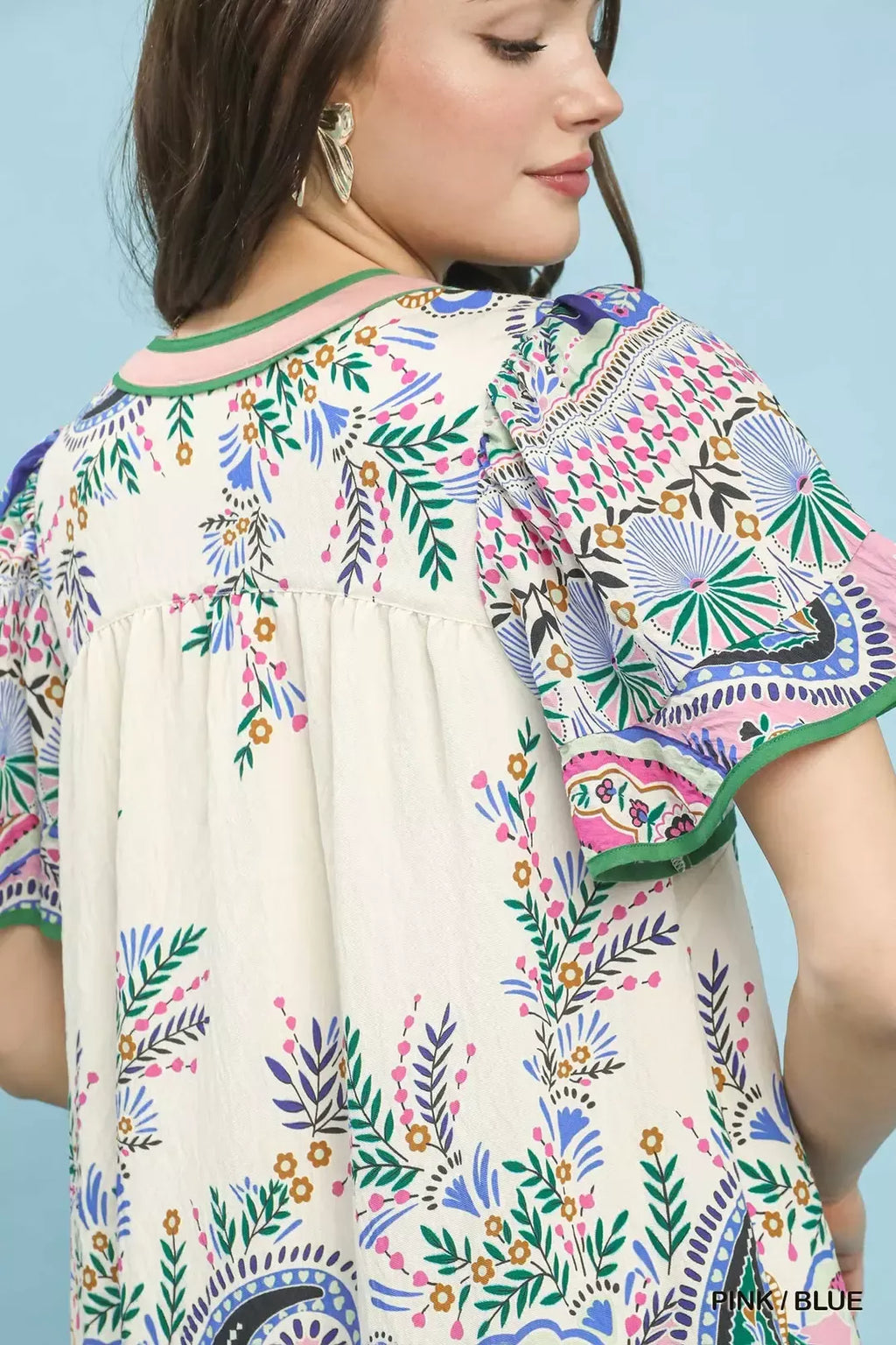 Close-up: Pink/Blue paisley mini dress top with green-trim V-neck and puffed seam