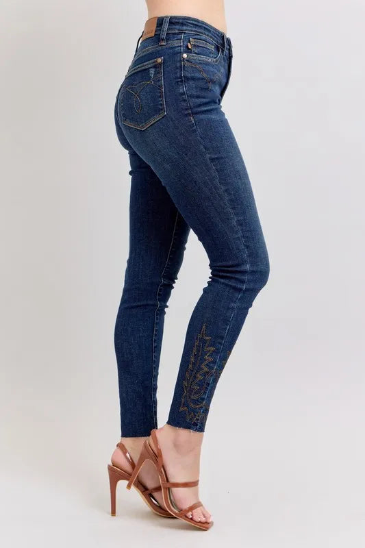 Dark blue skinny jeans, back view with embroidered ankle trim