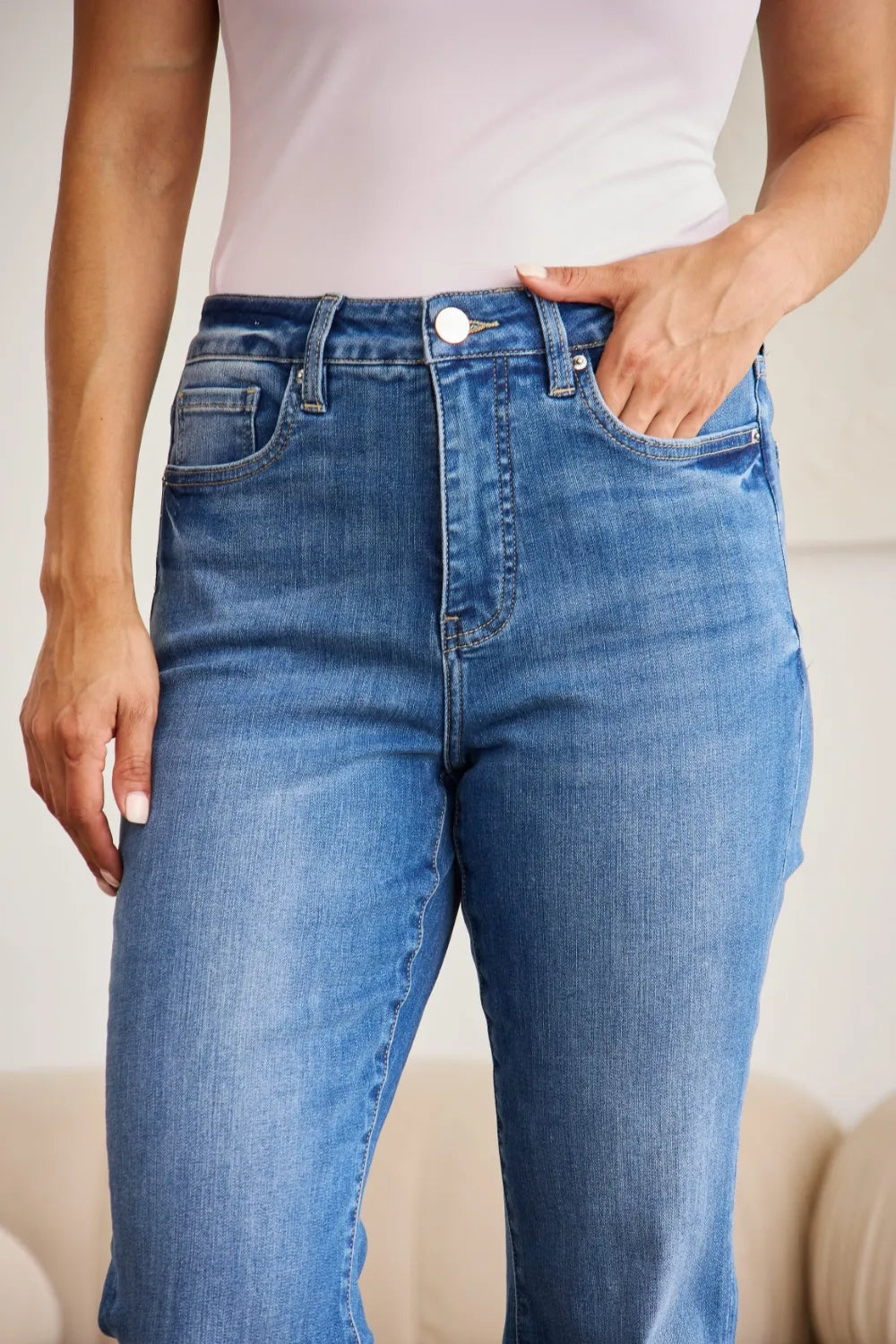 Front close-up: medium wash high-waist tummy-control jeans with button and front pockets