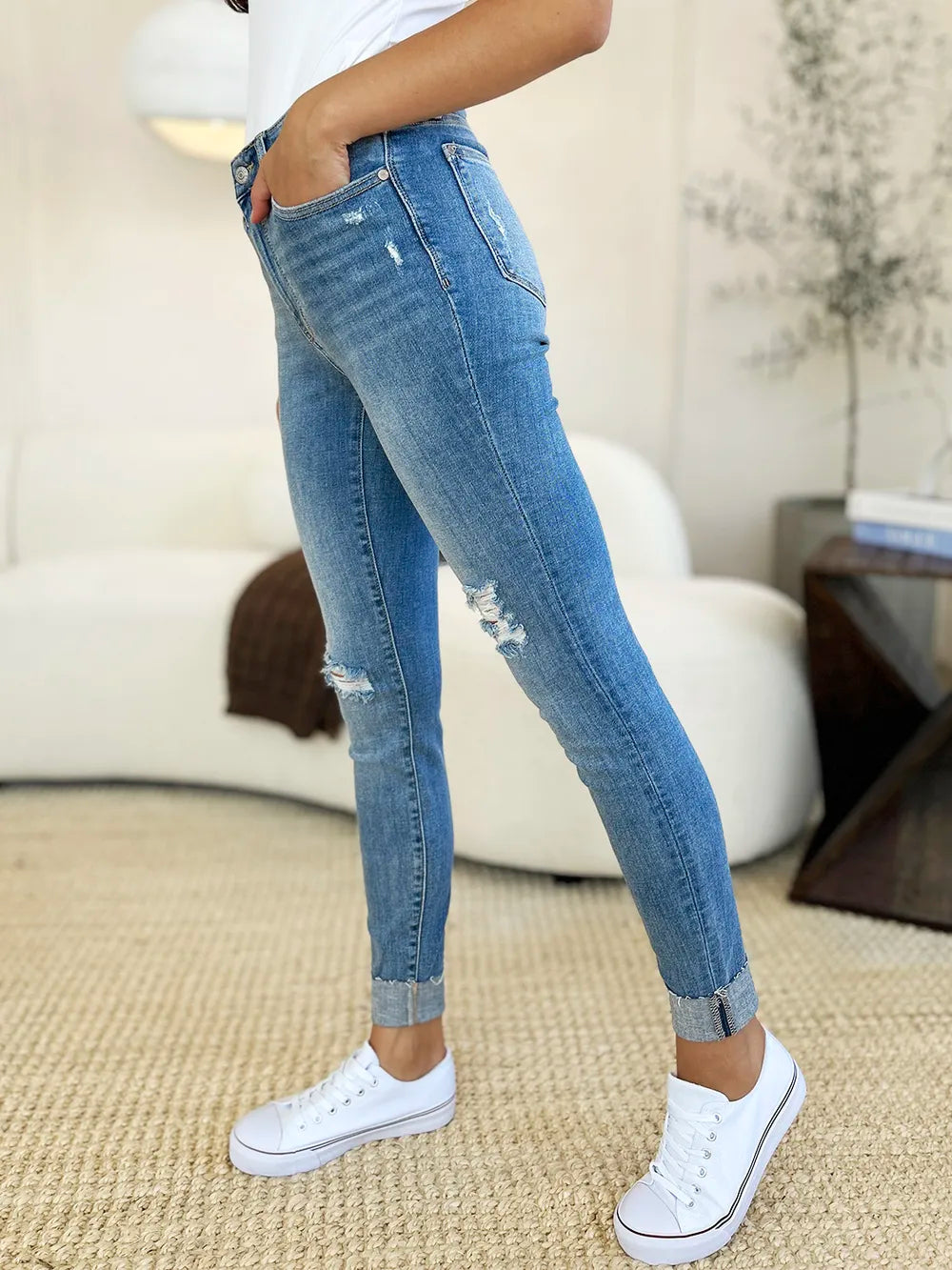Front side: medium wash mid rise skinny jeans with thigh and knee distress