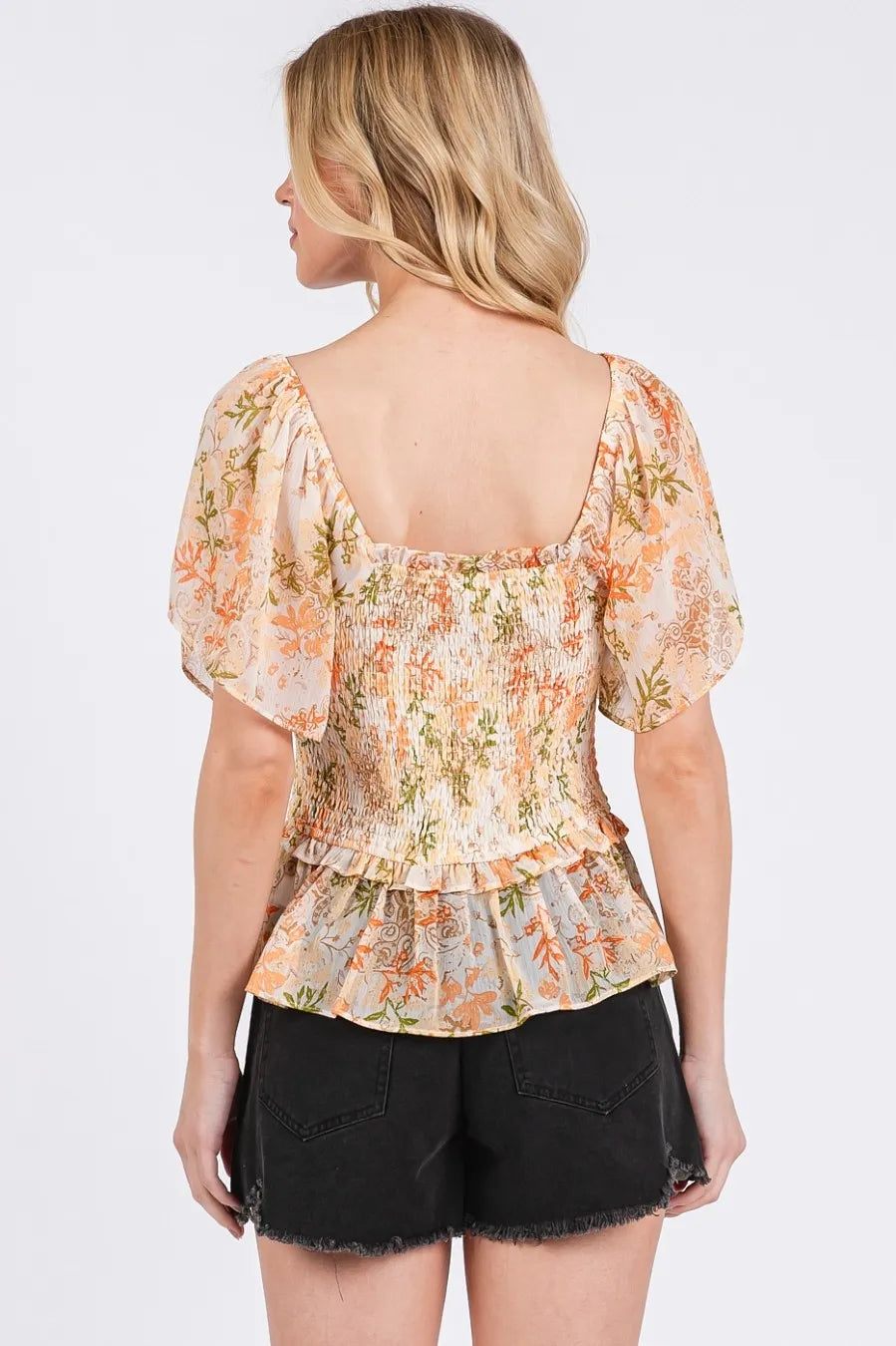 Back view of orange floral chiffon peplum top with square smocked yoke