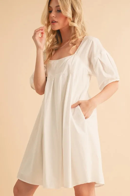 White square-neck babydoll dress with short puff sleeves and pleated front