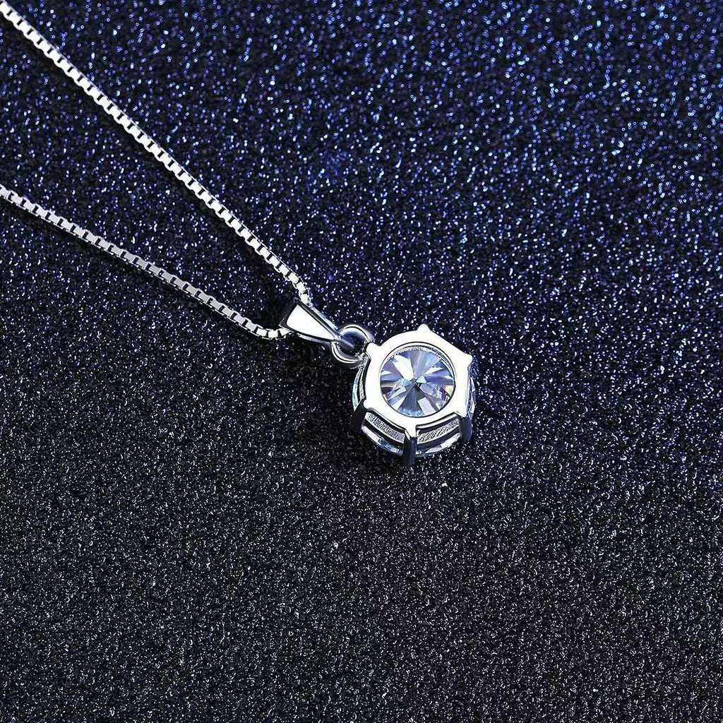 Close-up of round moissanite pendant with faceted star design on sterling silver chain