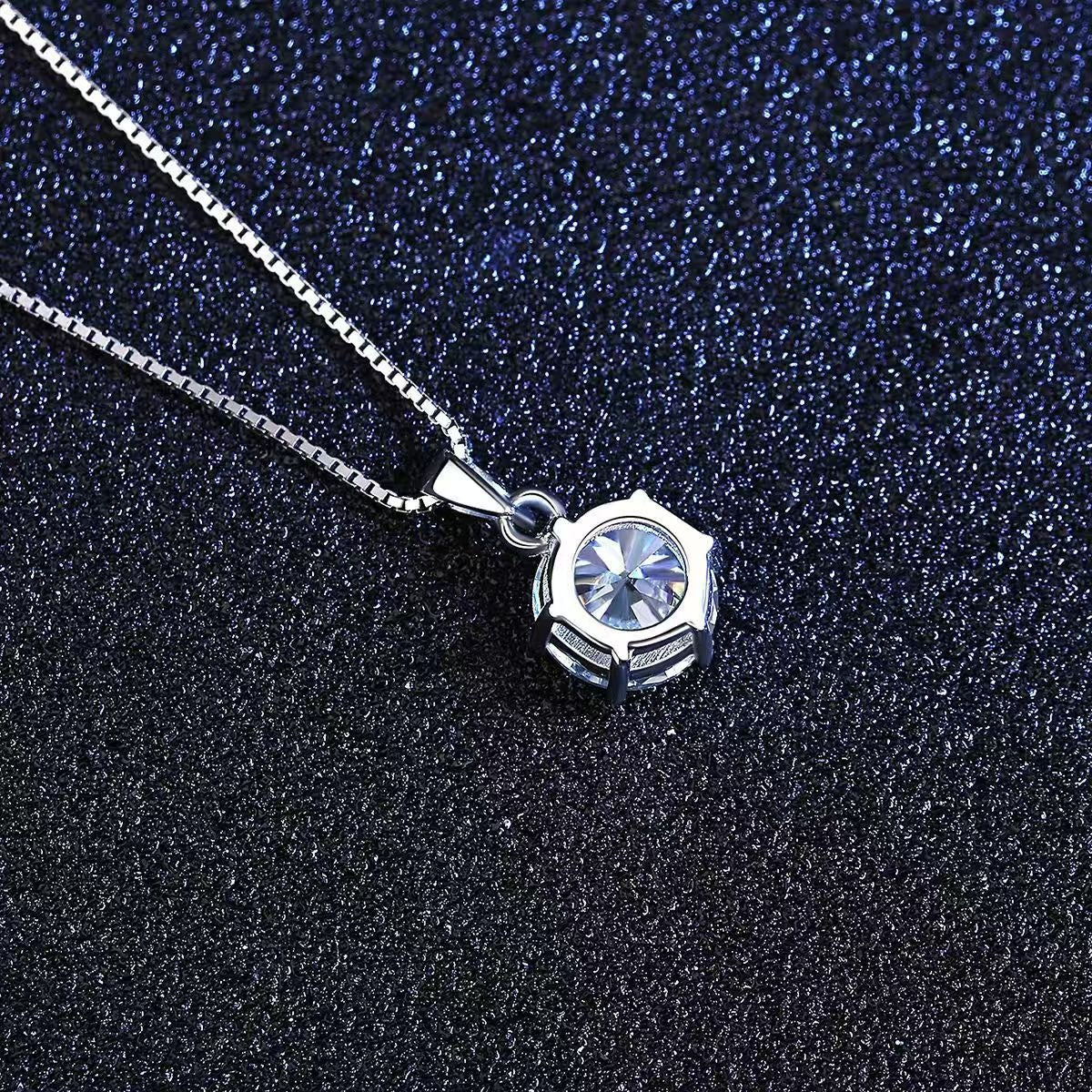 Close-up of round moissanite pendant with faceted star design on sterling silver chain