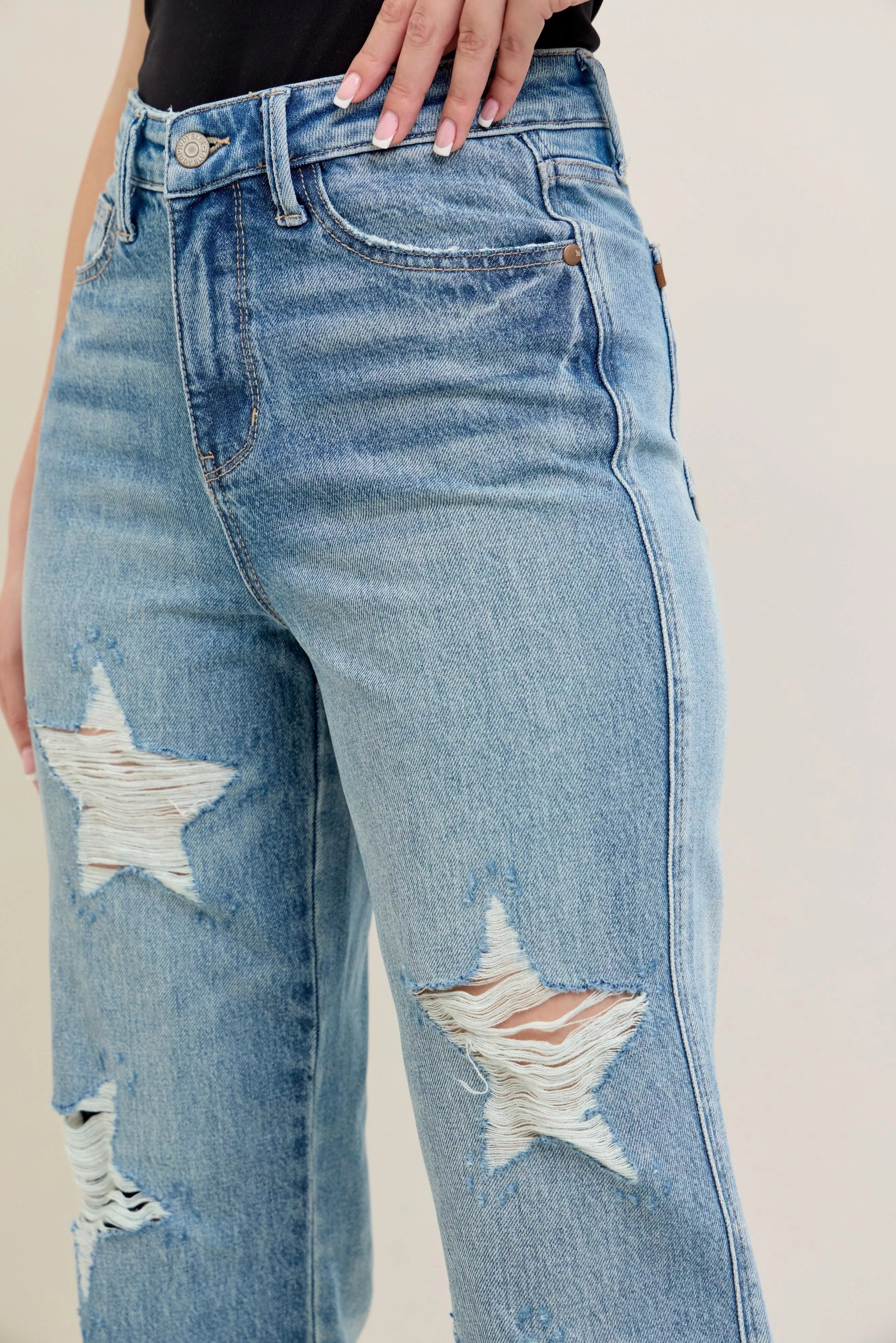 Back view: light denim high-waist jeans with star-shaped distressed rips