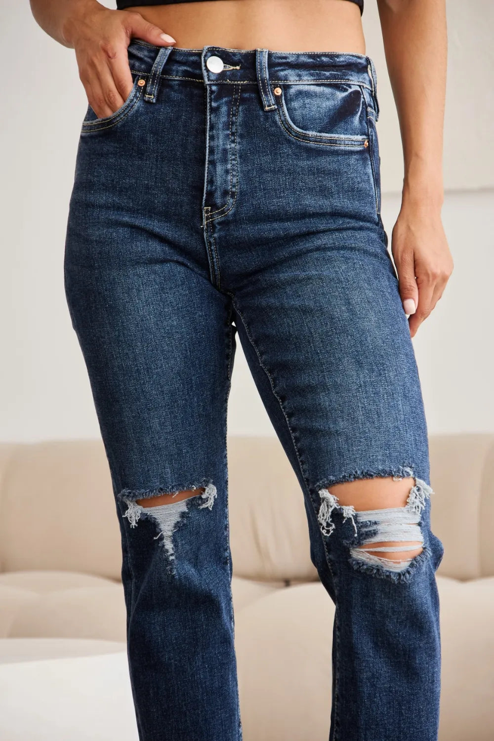 Front close-up: dark-wash high-waist jeans, raw hem and frayed knee rips