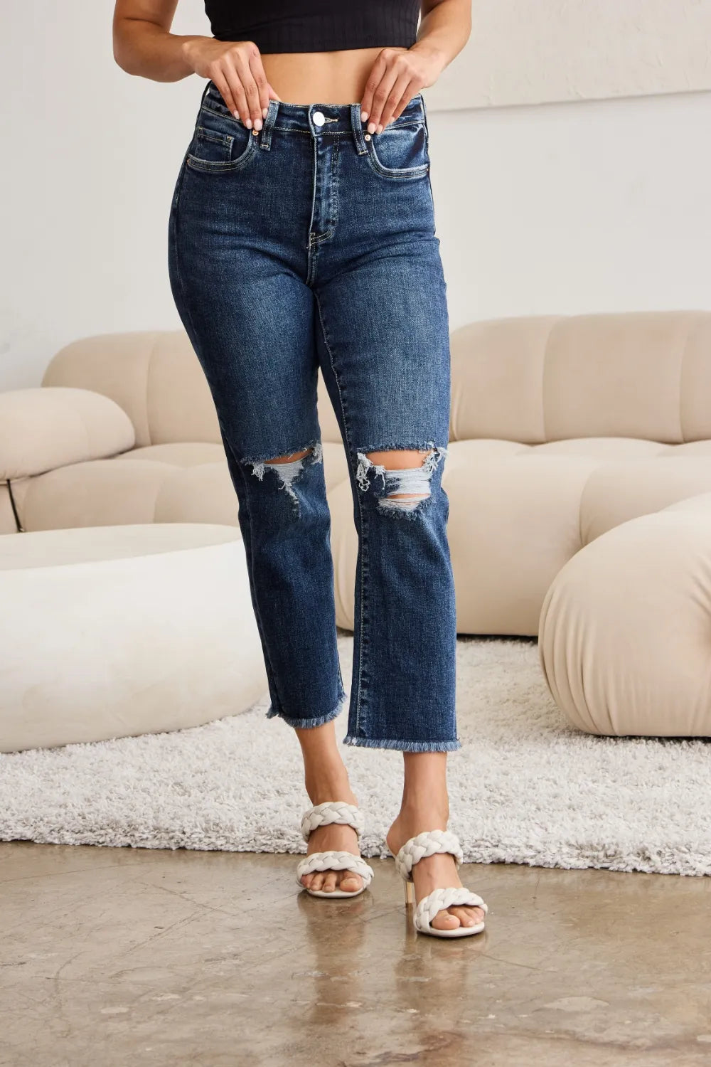 Dark blue high-waist jeans front view with ripped knees and straight raw hems