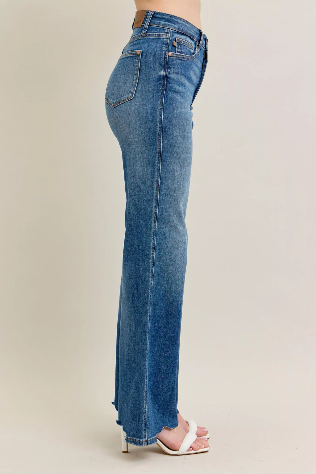 Side view: medium-wash wide-leg jeans with distressed pocket and frayed hem
