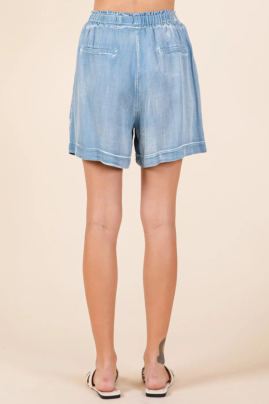 Back view of light denim chambray shorts with elastic waistband and relaxed fit