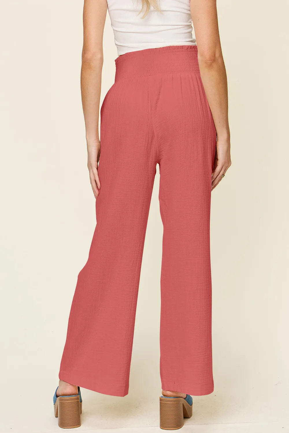 Hot pink smocked-waist wide-leg pants, back view, textured woven fabric