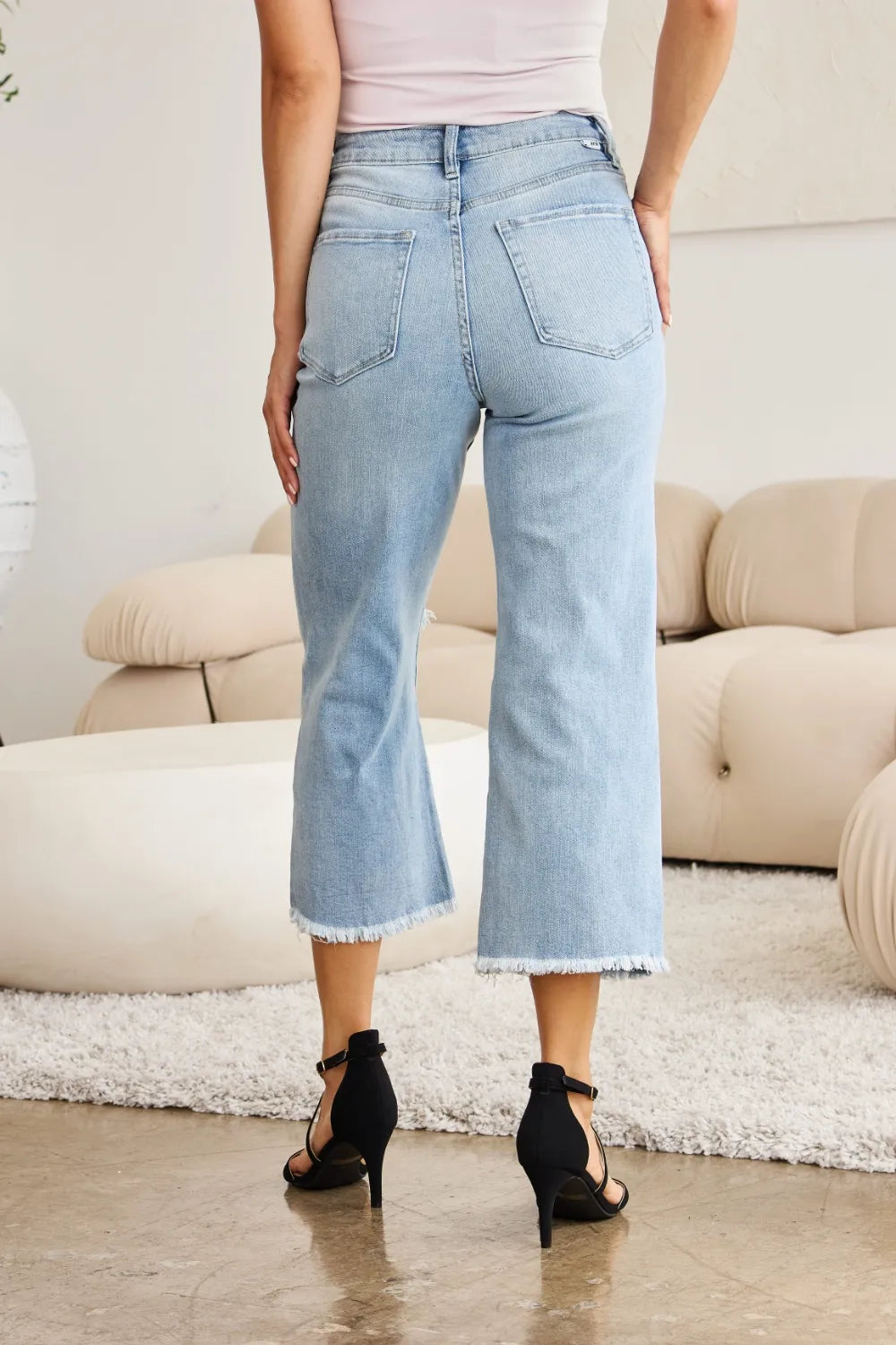 Light wash high-waist jeans with frayed cuffs and back pockets, straight cropped fit