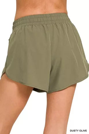 Dusty olive lined shorts with elastic waistband and relaxed fit; side zip coin pocket