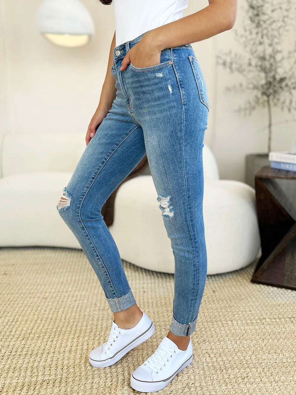Side view: medium wash skinny jeans with knee rips and frayed cuff hem