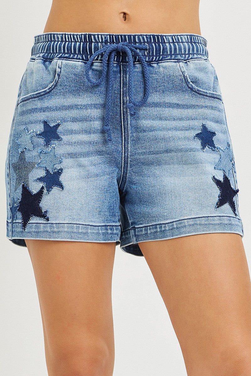 Close-up of denim shorts waistband with drawstring and star patches on the legs