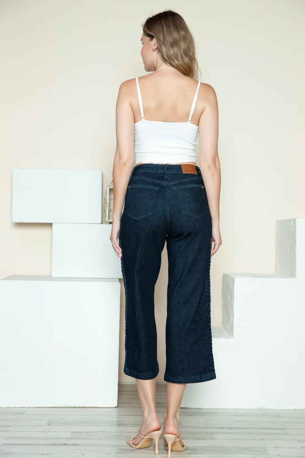 Dark denim wide-leg crop jeans back view with braided seam detail on the outer leg