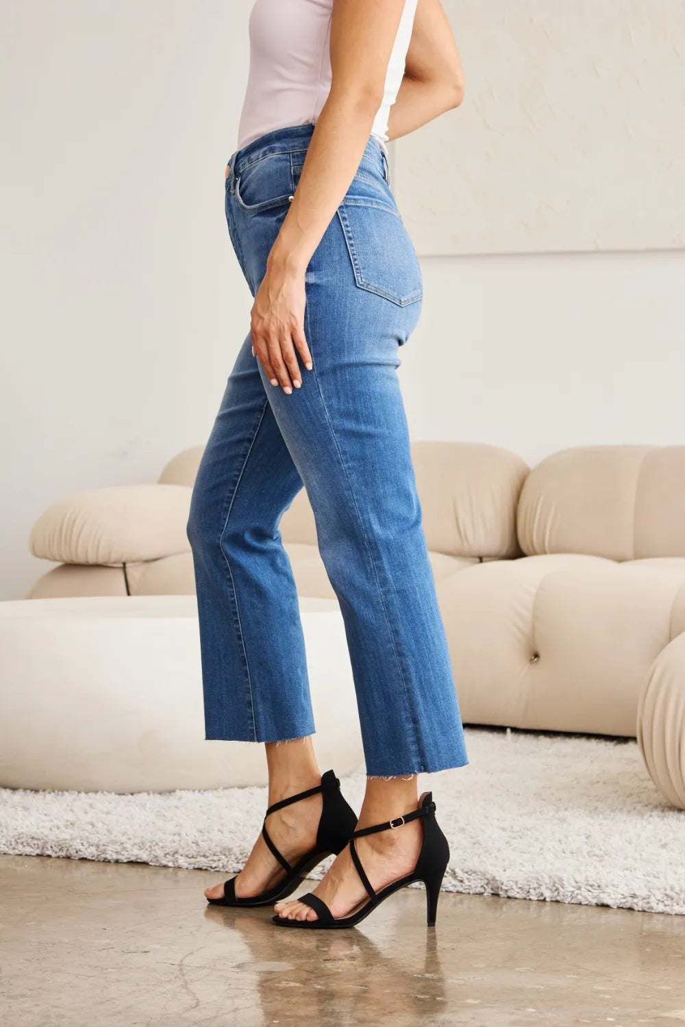 Side view of medium blue tummy-control high-waist jeans with slant front pockets and belt loops