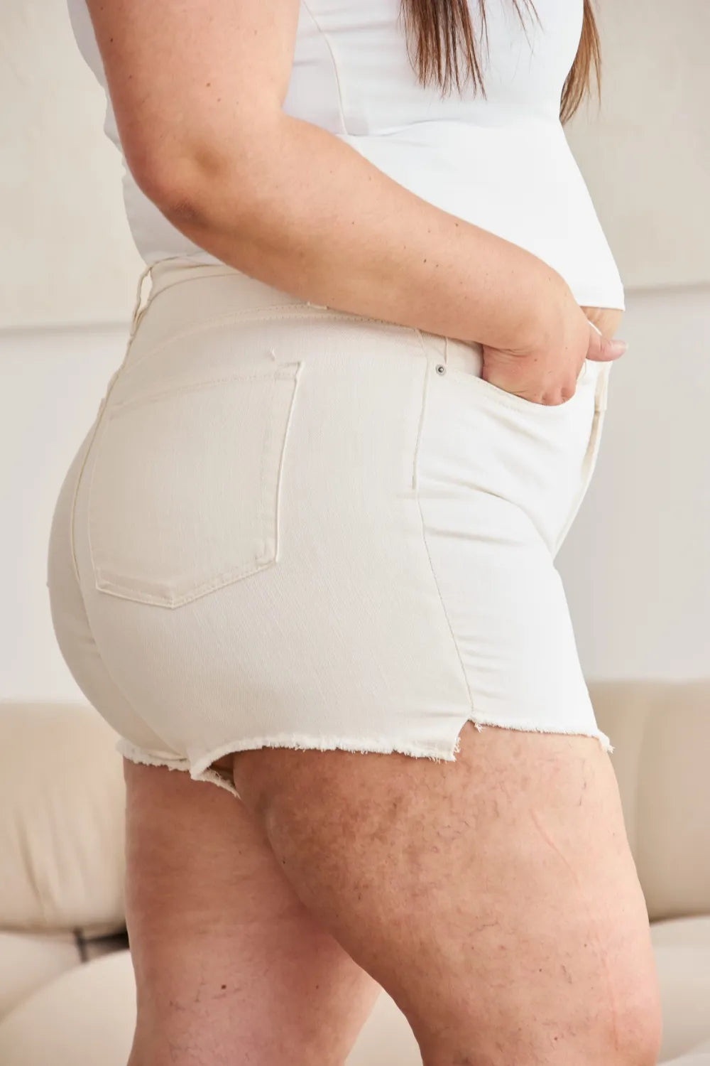 Off-white high-waist denim shorts, back pocket detail and frayed hem edge