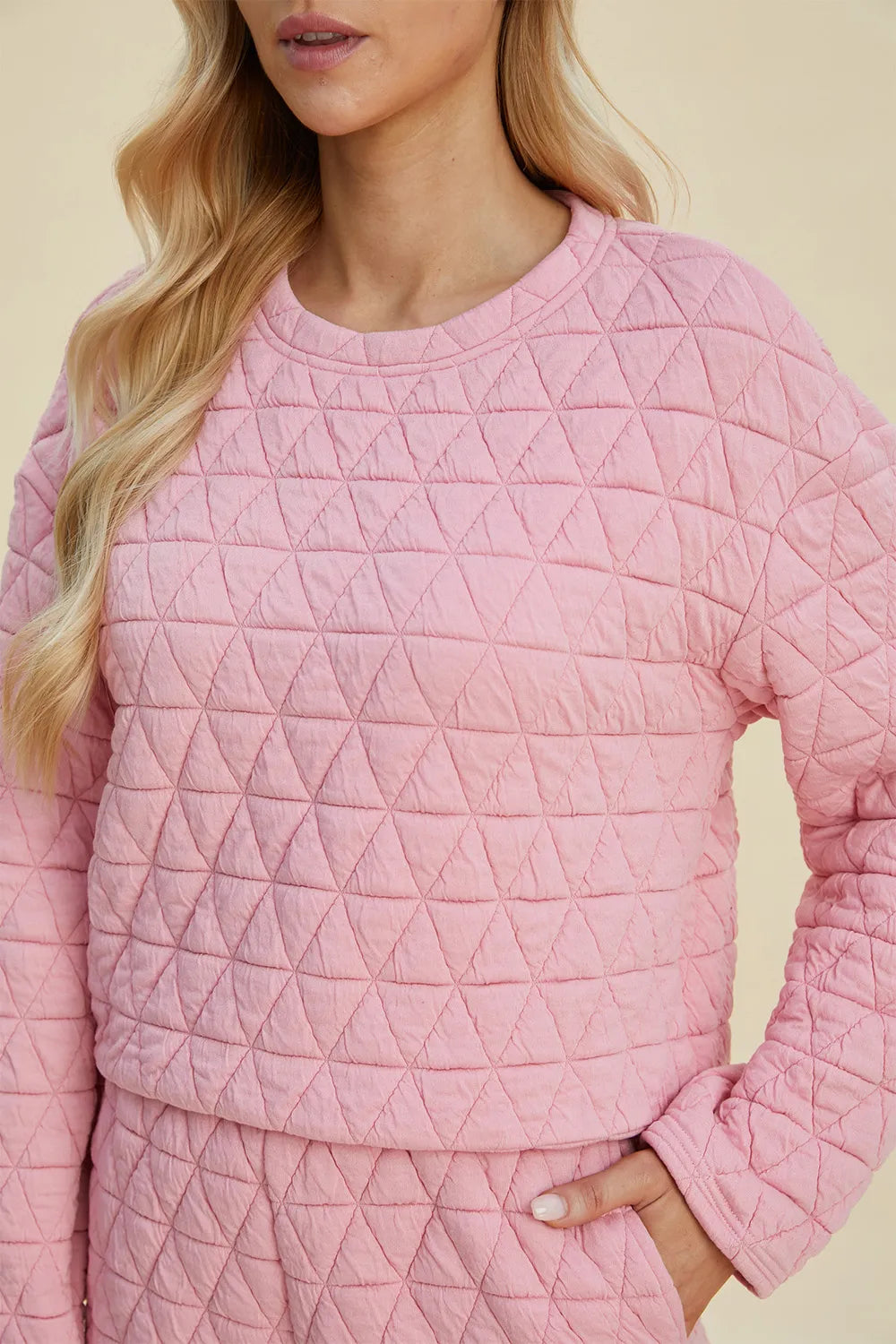 Pink quilted long-sleeve top with round neck, geometric triangle texture detail.