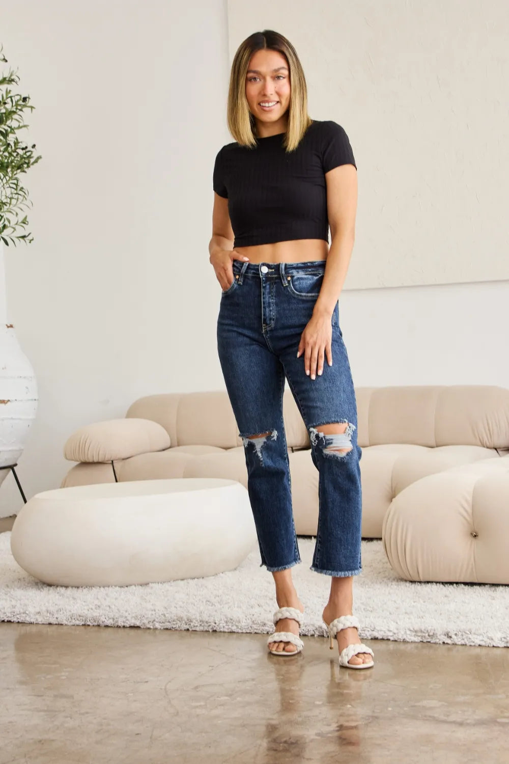 Dark blue high-rise distressed jeans with knee rips and raw cuff detail