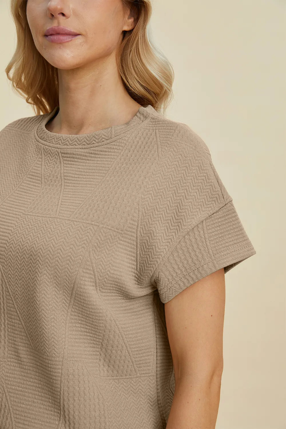 Close-up: khaki textured crew-neck short-sleeve top with stitched pattern detail