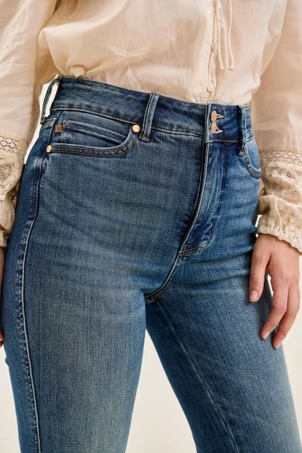 Dark denim high-waist jeans close-up, double-button waistband with belt loops