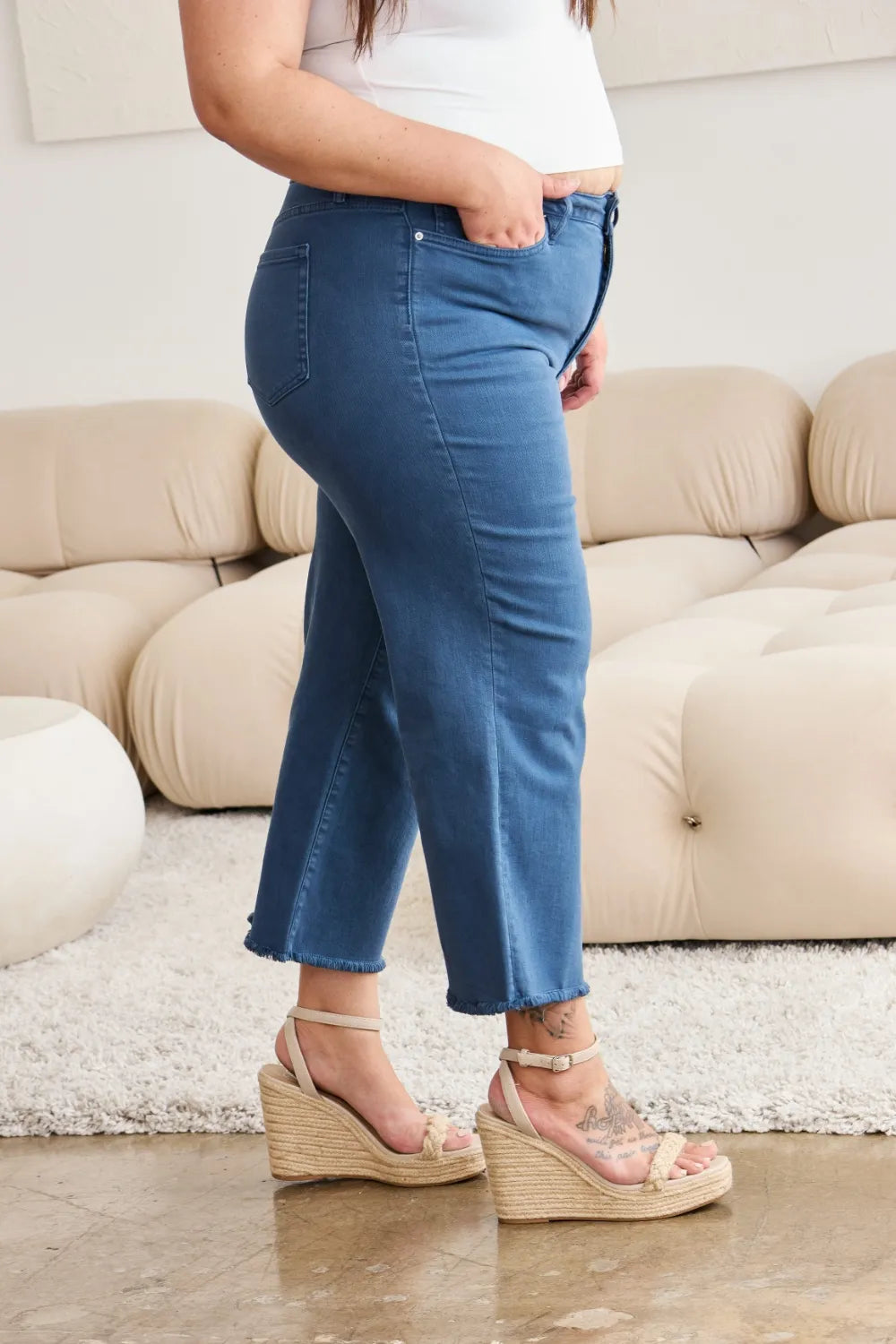 Jeans front: blue high-rise denim with button closure and raw bottom hem