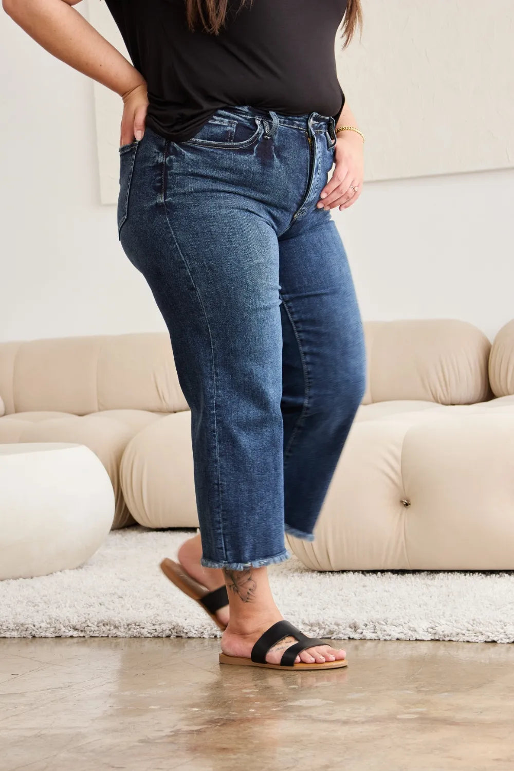 Dark wash high-waist jeans with raw hem, subtle fading and distressed styling