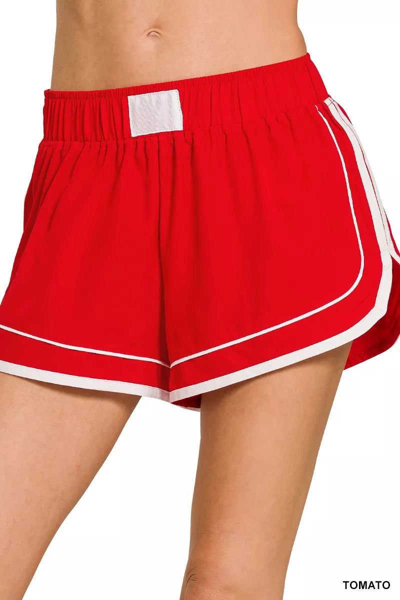 Tomato red dolphin shorts with elastic waistband and white contrast trim