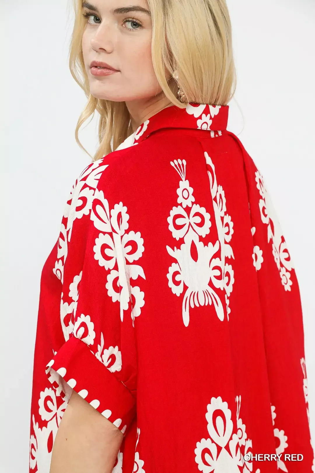 Cherry red short-sleeve button-down shirt with large white floral motifs on back