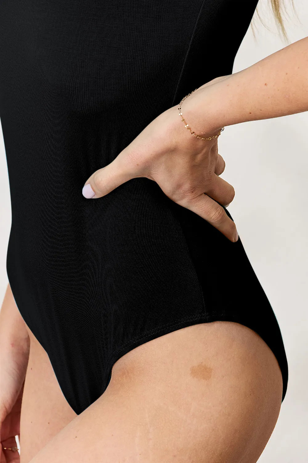 Black bodysuit fabric close-up at waist seam and high leg opening