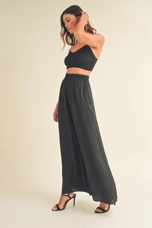 Conjunto negro de lado: bralette corto y pantalón ancho con cintura elástica fruncida