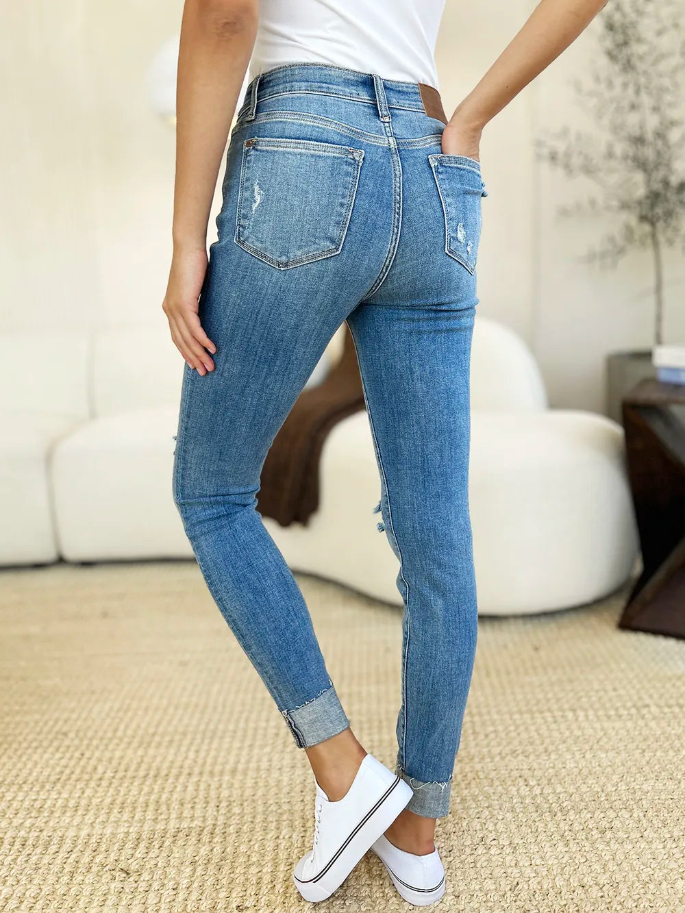 Medium blue mid-rise skinny jeans with destroyed details and cuffed hem