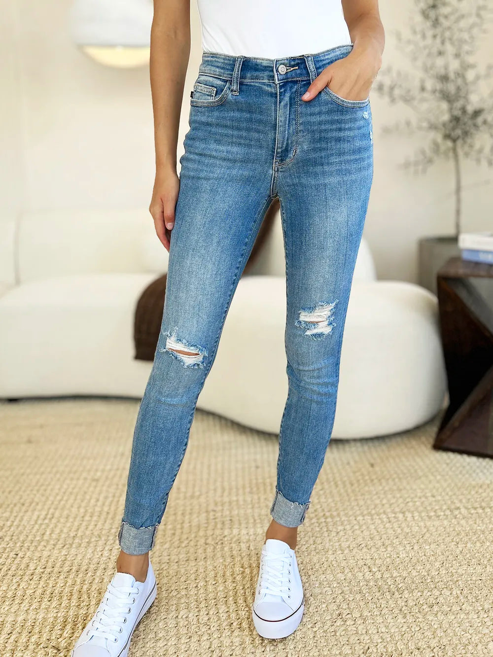 Front view: medium wash skinny jeans with diagonal knee distress and cuffed ankles