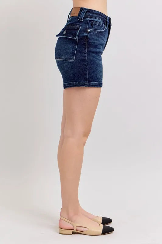 Side view dark denim shorts with high-rise waistband, belt loops, and flap pocket