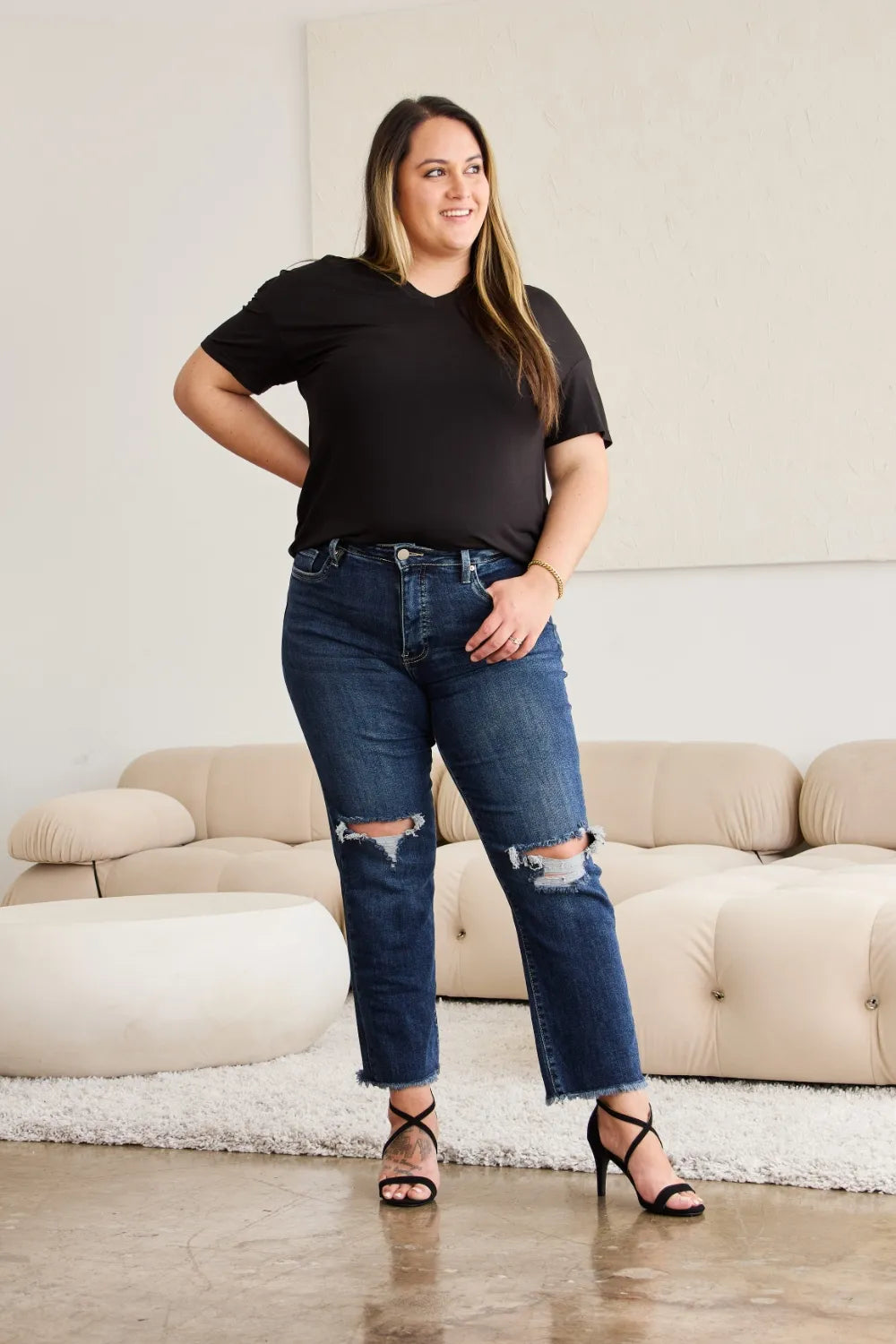 Dark-wash high-rise jeans with distressed knees and frayed raw-hem cuffs