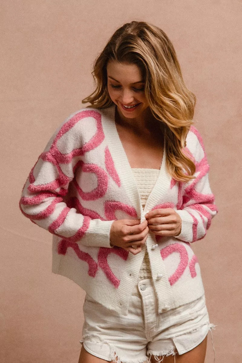 Cardigan blanco con botones, manga larga y corazones rosa en tejido grueso