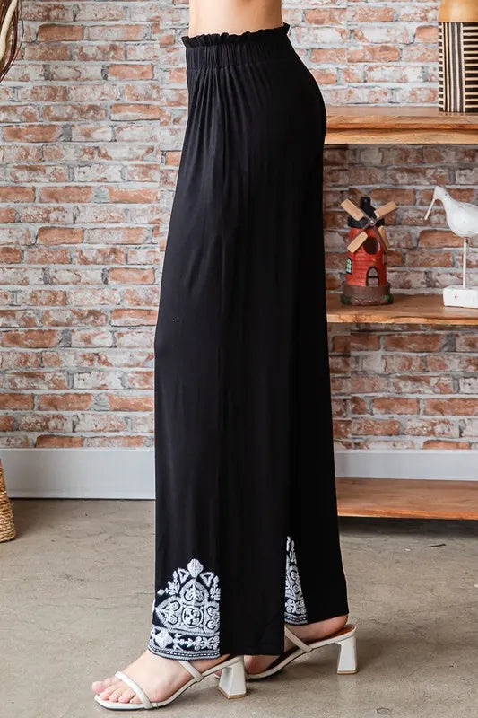 Black flowy wide-leg pants with elastic waist and white patterned hemmed cuffs