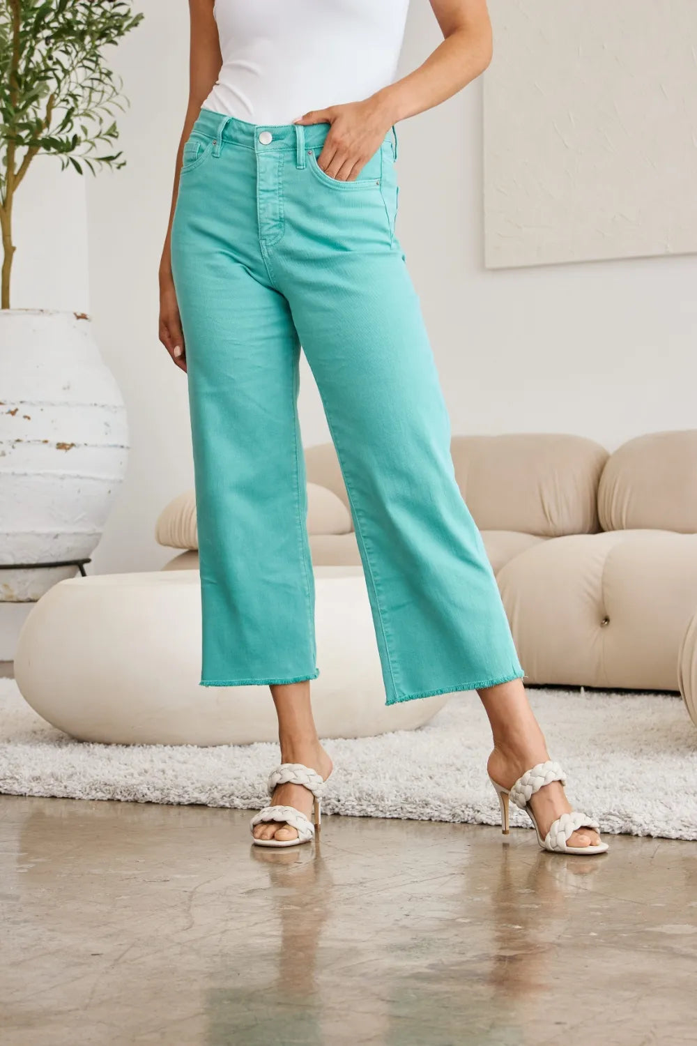 Island Green jeans close-up on legs: high rise, straight flare, raw hem