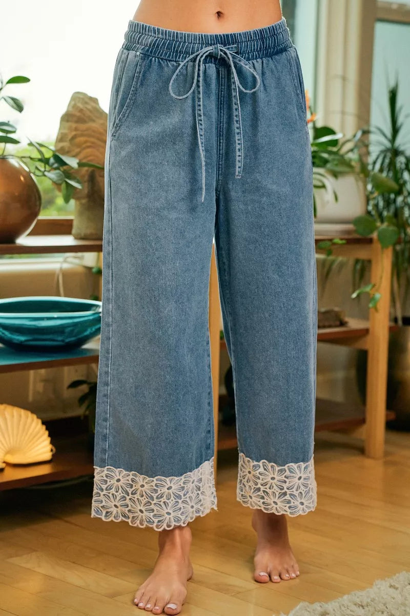 Washed denim wide-leg pants with elastic waistband, drawstring tie, and lace flower hem