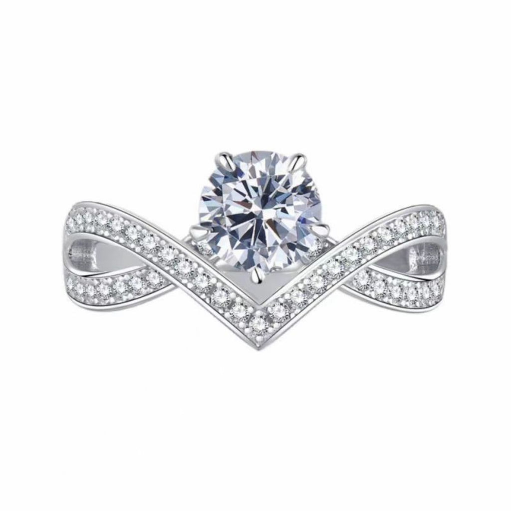 Moissanite ring on white background: round center stone, V-shaped pavé band