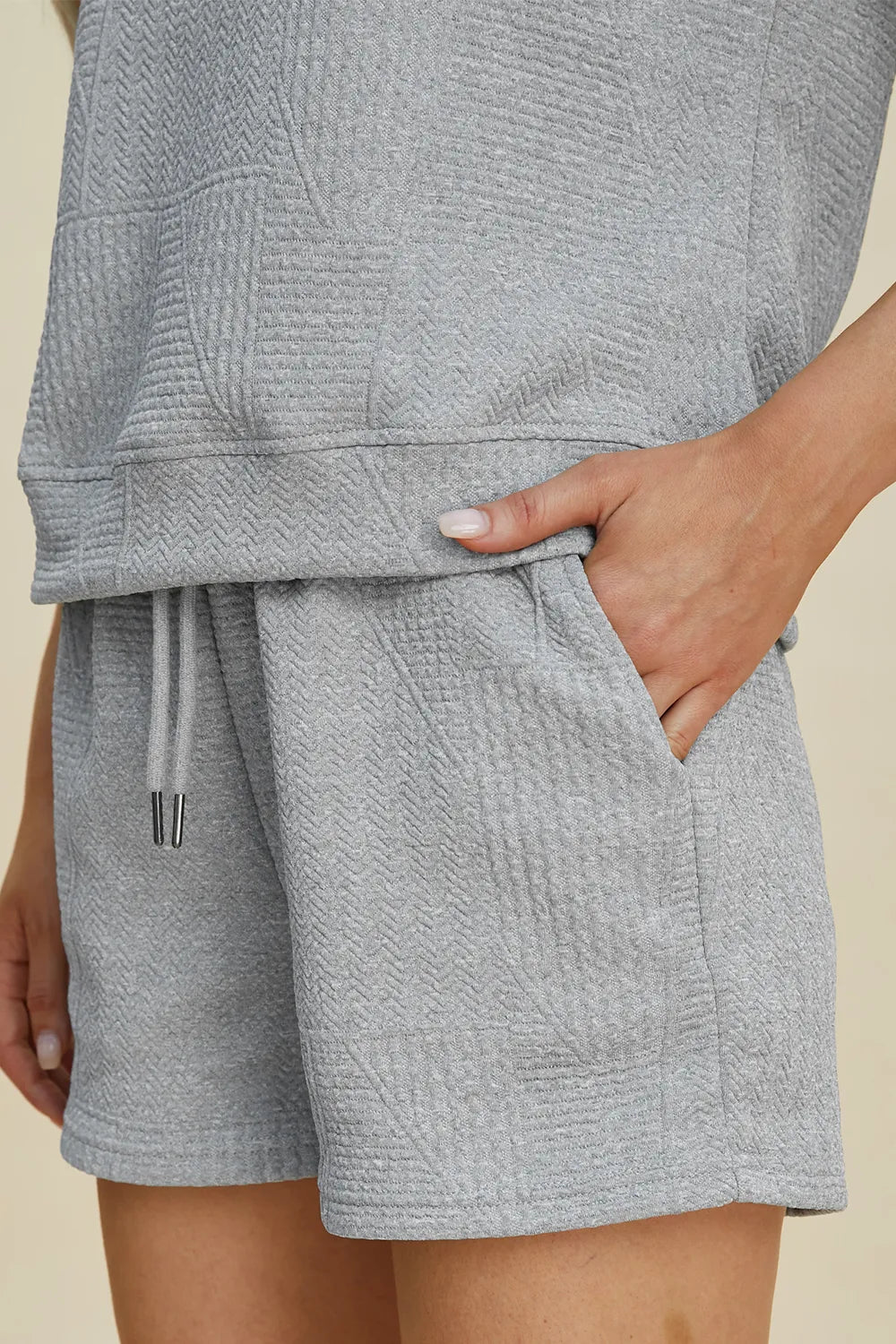 Gray textured shorts set close-up: drawstring, stitched panels, and matching top hem