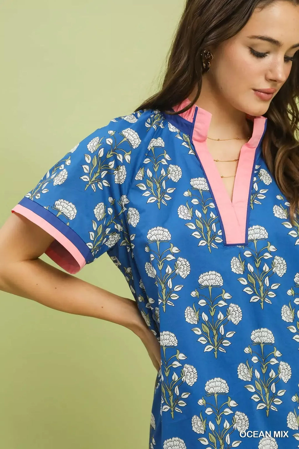 Close-up of blue floral shift dress neckline with V split and pink trim