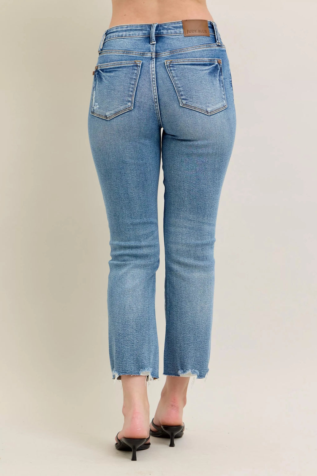 Medium-wash kick flare jeans, back view with frayed bottom hem