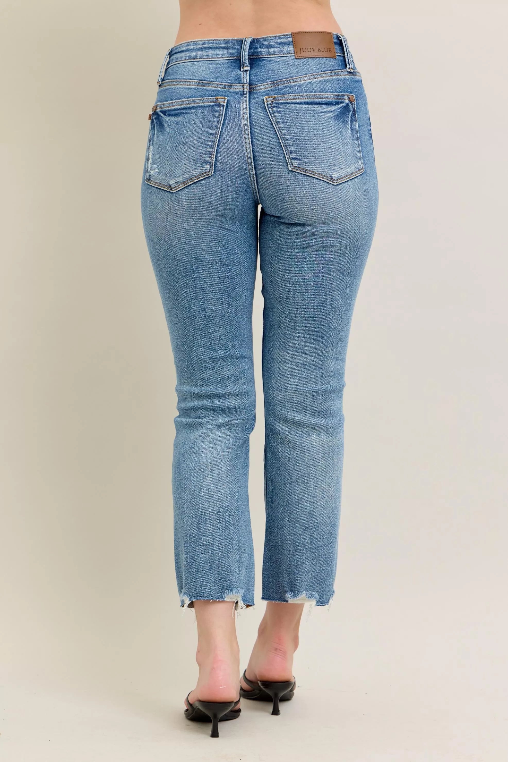 Medium-wash kick flare jeans, back view with frayed bottom hem