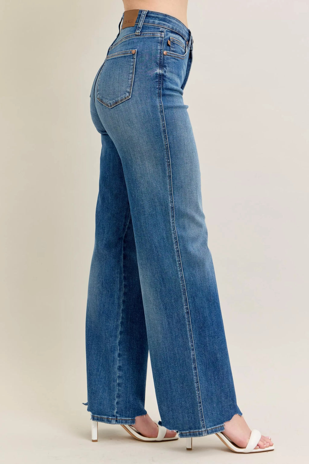 Side-back view: medium-wash wide-leg jeans with raw hem and subtle fading